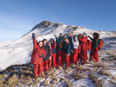 Winter mountain walking trip with school group in snow