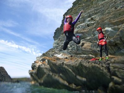 Coasteering jump into sea while outdoors in Wales